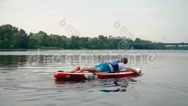 年轻人躺在皮划艇上，双<strong>手划船</strong>